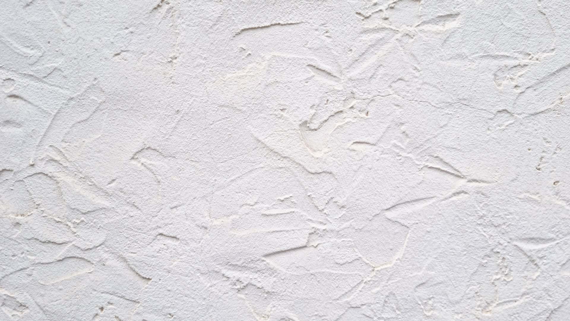 White decorative plaster wall texture with uneven rough surface and abstract pattern. Interior construction material photography. Background with space for text. Mockup stage template